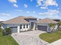 A stunning exterior view of a home with well-kept landscaping, two garage spaces, and a brick driveway at 8936 Sanders Tree Loop, Wesley Chapel, FL 33545
