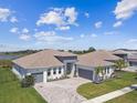 An elevated view of a home with two garage spaces, brick driveway, lush lawn, and lake view at 8936 Sanders Tree Loop, Wesley Chapel, FL 33545
