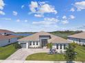 A partial aerial view of a house with a brick driveway, two garage spaces, and a manicured lawn near a serene lake at 8936 Sanders Tree Loop, Wesley Chapel, FL 33545