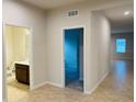Hallway showcasing tile floors leading to a bathroom and carpeted bedroom at 29307 Meadowcroft Ave, Wesley Chapel, FL 33544