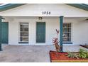 Inviting home entrance showcasing painted brick, complemented by freshly manicured landscaping and a well-lit porch area at 1024 Applewood Dr, Clearwater, FL 33759