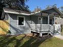A quaint home featuring a covered front porch, grey siding, and freshly landscaped yard at 8306 N Orleans Ave, Tampa, FL 33604