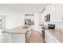 Open-concept kitchen boasting stainless steel appliances, granite countertops, white cabinets, and tile floors at 1752 Brekey Way, Zephyrhills, FL 33541