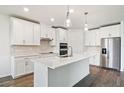 Modern kitchen with stainless steel appliances, white cabinets, and a large center island with white marble countertop at 1787 Draughton Dr, Zephyrhills, FL 33541