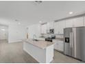 Bright, open-concept kitchen featuring white cabinets, stainless steel appliances, and a large island with granite countertops at 1861 Brekey Way, Zephyrhills, FL 33541