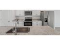 Modern kitchen featuring white cabinets, stainless steel appliances, a granite countertop, and a stainless steel sink at 1861 Brekey Way, Zephyrhills, FL 33541