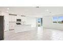 Open-concept living space with white tile floors, modern kitchen and natural light at 1870 Draughton Dr, Zephyrhills, FL 33541