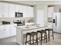 Bright kitchen featuring white cabinets, stainless steel appliances, and an island with bar seating at 233 Lazy Shore Dr, Nokomis, FL 34275