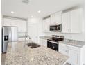 Close-up view of a kitchen featuring stainless steel appliances, white cabinets, and granite countertops at 31643 Wild Grape Ln, Brooksville, FL 34602