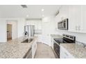 Bright, open kitchen featuring modern appliances, granite countertops, and sleek white cabinetry at 31643 Wild Grape Ln, Brooksville, FL 34602
