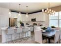 Modern kitchen with white cabinets, stainless steel appliances, pendant lighting, and a dining area at 9548 Vibrant Lane, Venice, FL 34292