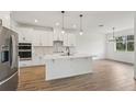 Modern kitchen with an island, stainless steel appliances, and light hardwood floors at 14035 Kelly Park Ct, Parrish, FL 34219