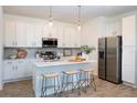 Bright kitchen featuring white cabinets, stainless appliances, quartz counters, and island seating for a modern culinary space at 17378 Alderwood Ln, Punta Gorda, FL 33982