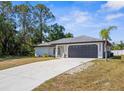 This single-story home boasts a spacious driveway, a gray roof, and mature landscaping at 4284 Persian Ln, North Port, FL 34287