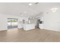 Bright living room featuring wood-look floors, an island, updated lighting, and an open-concept design at 4284 Persian Ln, North Port, FL 34287