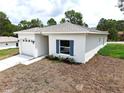 A modern single-story home showcasing a side entry garage, a window with blue shutters, and fresh landscaping at 8990 Glenarm Way, Weeki Wachee, FL 34613
