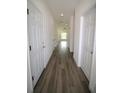 Long hallway with multiple white doors, recessed lighting, and wood-look flooring throughout at 8990 Glenarm Way, Weeki Wachee, FL 34613