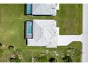 Aerial view of a home featuring a private pool enclosed in a screen, alongside a paved driveway and lush landscaping at 221 Rotonda S Blvd, Rotonda West, FL 33947