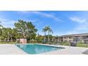 Community pool surrounded by lush trees, lounge chairs, and a grill, perfect for outdoor relaxation at 721 83Rd N Ave # 108, St Petersburg, FL 33702