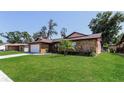 Exterior view of a charming house with a large grassy lawn, mature trees, and a stone facade at 1117 Mook St, Brandon, FL 33510