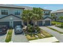 Attractive townhome with a paved driveway, two-car garage, and manicured landscaping, with mature palm trees at 15242 Sunny Day Dr, Bradenton, FL 34211
