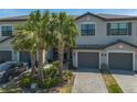 Well-kept townhome featuring a two-car garage, paved driveway, and mature palm trees in a landscaped yard at 15242 Sunny Day Dr, Bradenton, FL 34211