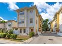 A three-story townhouse with a cream-colored facade, yellow accents, and a well-maintained landscaped front yard at 4409 W Gray St # 5, Tampa, FL 33609