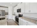 Modern kitchen with stainless steel appliances, granite countertops, and white cabinetry at 7740 Gilchrist Springs Dr, Parrish, FL 34219