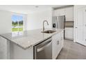 Stylish kitchen island with granite countertops, a stainless steel dishwasher, and a view of the backyard at 7740 Gilchrist Springs Dr, Parrish, FL 34219