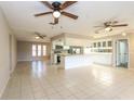 Bright living room featuring tiled floors, ceiling fans, and an open layout to the kitchen at 12408 Golden Oak Cir, Hudson, FL 34669