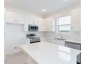 Bright white kitchen features stainless steel appliances, an island with a quartz countertop, and white subway tile backsplash at 42858 Park View Dr, Punta Gorda, FL 33982