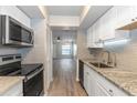 Galley kitchen with white cabinets and granite countertops, with a view to the living room at 2597 Countryside Blvd # 204, Clearwater, FL 33761