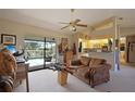 Cozy living room featuring a ceiling fan, sliding glass doors to the pool, and convenient kitchen access at 268 Cory St, Port Charlotte, FL 33953