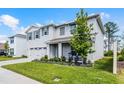 Charming two-story home featuring a well-manicured lawn, gray shutters, covered porch, and two-car garage at 1220 Tahitian Sunrise Dr, Plant City, FL 33565