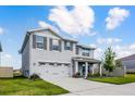 Charming two-story home featuring a well-manicured lawn, gray shutters, covered porch, and two-car garage at 1220 Tahitian Sunrise Dr, Plant City, FL 33565