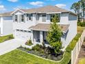 Charming two-story home featuring a well-manicured lawn, gray shutters, covered porch, and two-car garage at 1220 Tahitian Sunrise Dr, Plant City, FL 33565