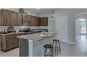Well-equipped kitchen featuring stainless steel appliances, granite counters, breakfast bar, and stylish bar stools at 1570 Hubbell Rd, Wesley Chapel, FL 33543