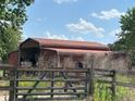 Exterior shot of a red barn with a metal roof and metal gate at 23046 Brandy Rd, Land O Lakes, FL 34639