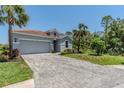 Paver driveway leading to a gray home with a tile roof and mature landscaping at 507 Daylily Blvd, Nokomis, FL 34275