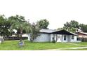 Exterior view of a grey house with well-kept landscaping, mature trees, and a grey roof at 2202 Whitney Pl, Valrico, FL 33594