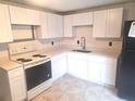 Bright kitchen featuring white cabinets, countertops, and appliances, with tile flooring at 3716 Mistwood Dr, Tampa, FL 33619