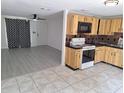 Eat-in kitchen featuring wood cabinetry, black countertops and black and tan backsplash and adjoining living area at 3716 Mistwood Dr, Tampa, FL 33619