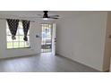 Bright living room featuring modern light gray wood flooring, a ceiling fan, and stylish patterned curtains at 3716 Mistwood Dr, Tampa, FL 33619
