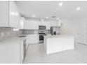 A bright and modern kitchen with white cabinets, stainless steel appliances, and a large center island at 9661 Summers Cay Cir, Thonotosassa, FL 33592