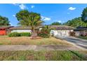 Well-maintained one-story home featuring a green lawn, mature trees, and an attached garage at 414 Mahogany Dr, Seffner, FL 33584