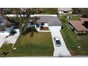 Aerial view of a single-story home with a green lawn, driveway, and well-kept landscaping at 20296 Rutherford Ave, Port Charlotte, FL 33952