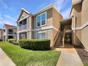 Exterior view of tan condo building with stairs leading to upper units and green grass at 9481 Highland Oak Dr # 609, Tampa, FL 33647