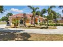 Beautiful orange stucco home featuring lush tropical landscaping, a red tile roof, and a circular driveway at 2202 Sparkman Rd, Plant City, FL 33566