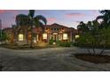 Stunning orange stucco home boasts a red tile roof, lush landscaping, and a circular driveway at twilight at 2202 Sparkman Rd, Plant City, FL 33566