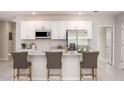 Modern kitchen with white cabinets, a stainless steel refrigerator, microwave, and a granite island with barstool seating at 25416 Jubal St, Punta Gorda, FL 33955